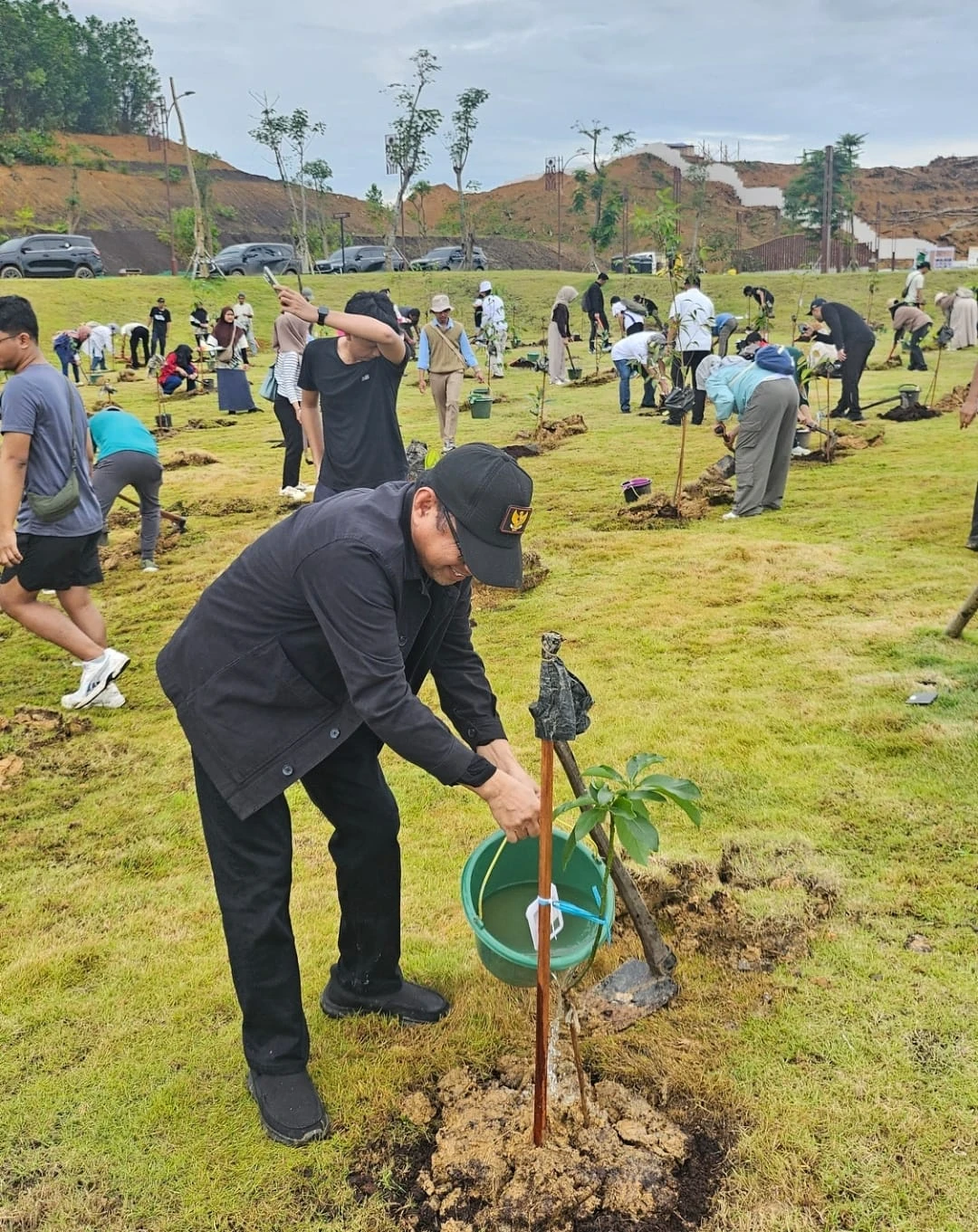 Rektor Universitas Balikpapan Isradi Zainal menyiram bibit pohon saat kegiatan penanaman bersama masyarakat di kawasan IKN Nusantara, Balikpapan, Kalimantan Timur, 1 Januari 2026, sebagai simbol komitmen akademisi dan warga dalam mendukung terwujudnya IKN sebagai kota hijau dan berkelanjutan.